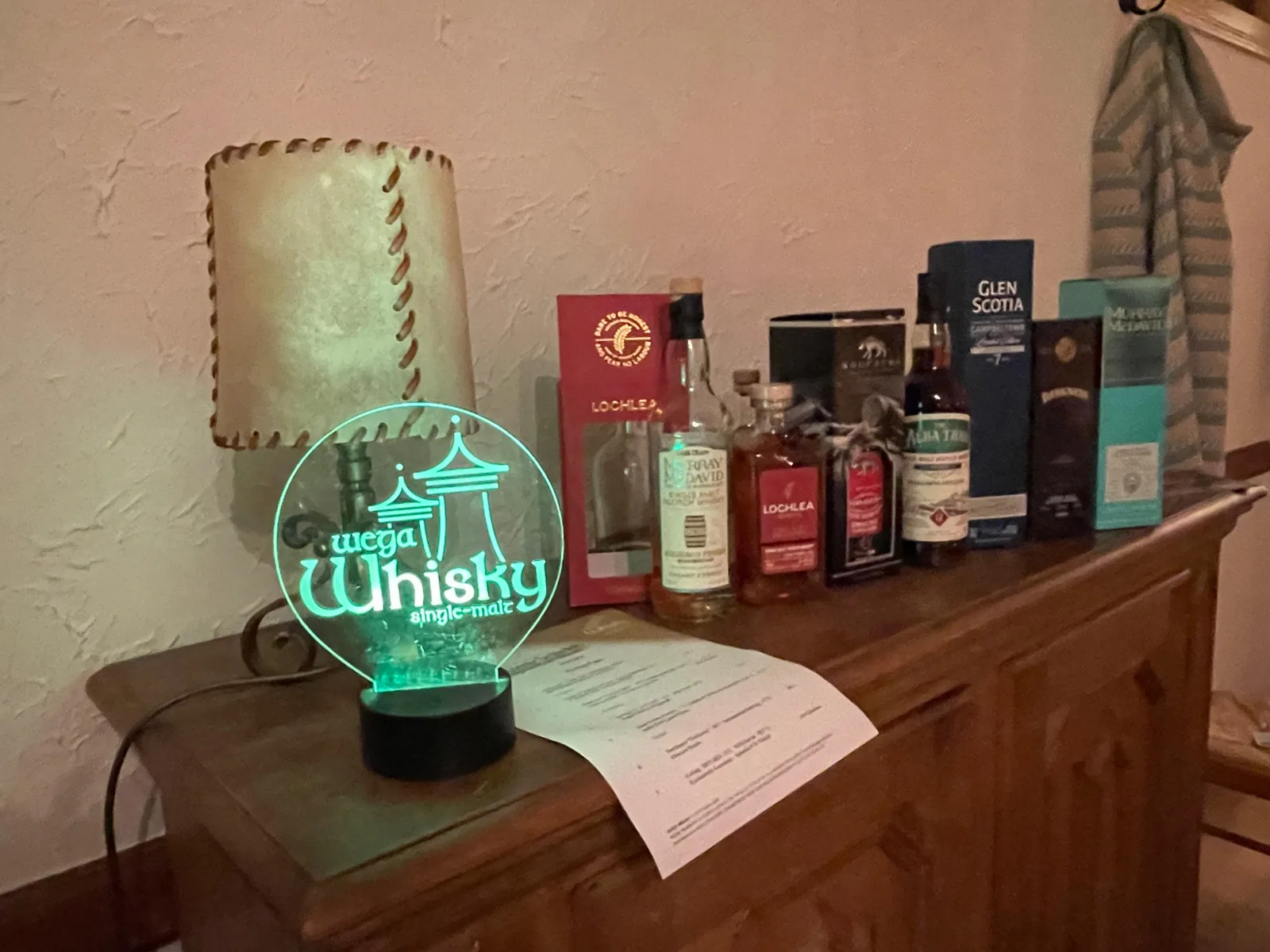 Whisky-Line-up neben leuchtendem WEGA-Whisky-Logo